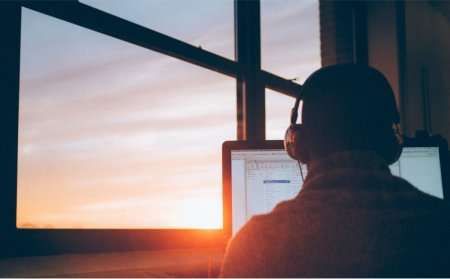 Counselling working online from their laptop with sunset in window